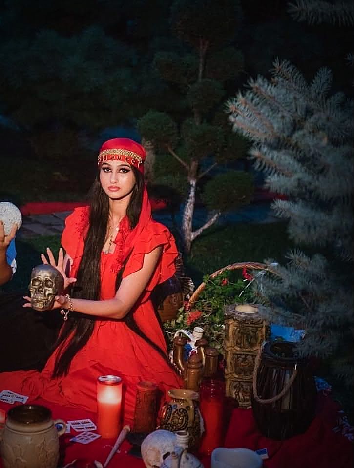 Loredana în rochie roșie, ținând un craniu ritualic