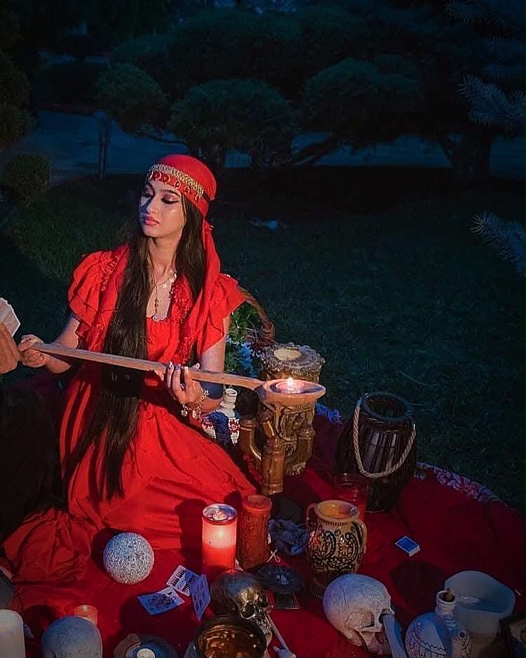 Vrăjitoarea Loredana la un ritual, în rochie roșie, printre lumânări